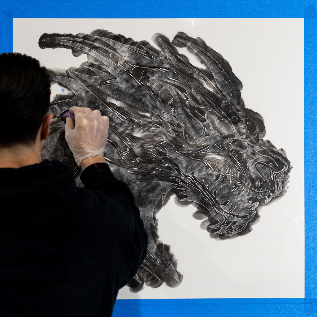 Intricate dragon stencil being painted on a wall