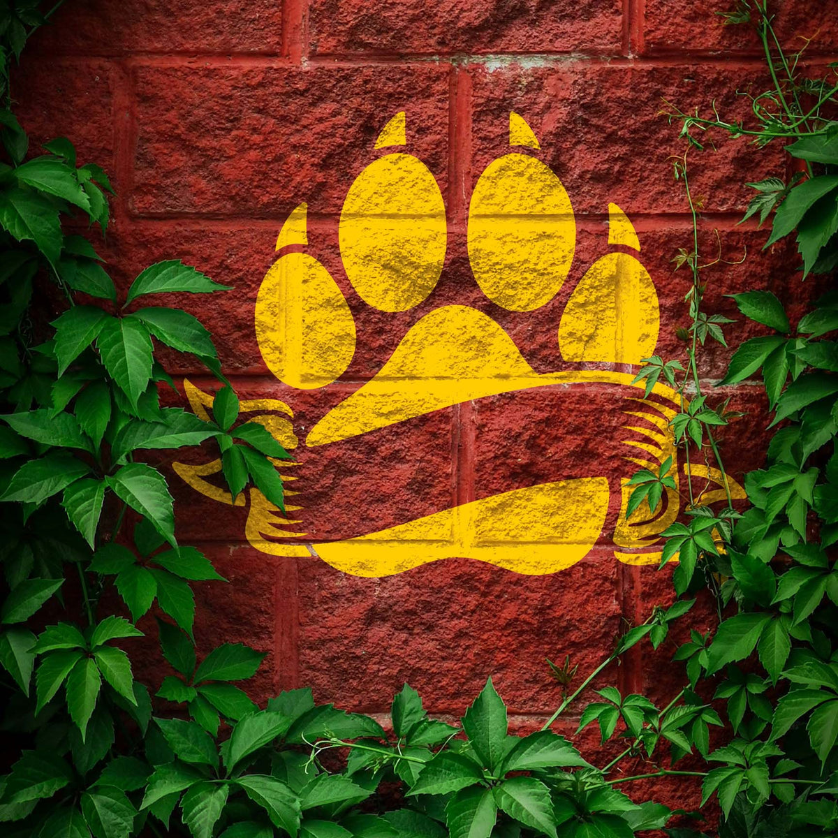 Vivid yellow Blank Banner Paw Print Stencil decorates a red brick wall surrounded by leafy vines
