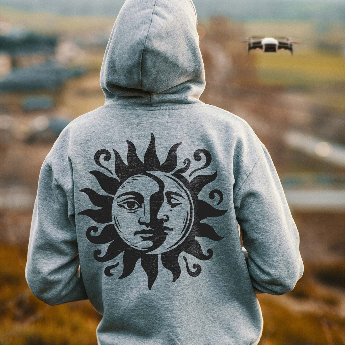 A gray hoodie features the Celestial Sun and Moon Face Stencil in black with swirling sun rays.