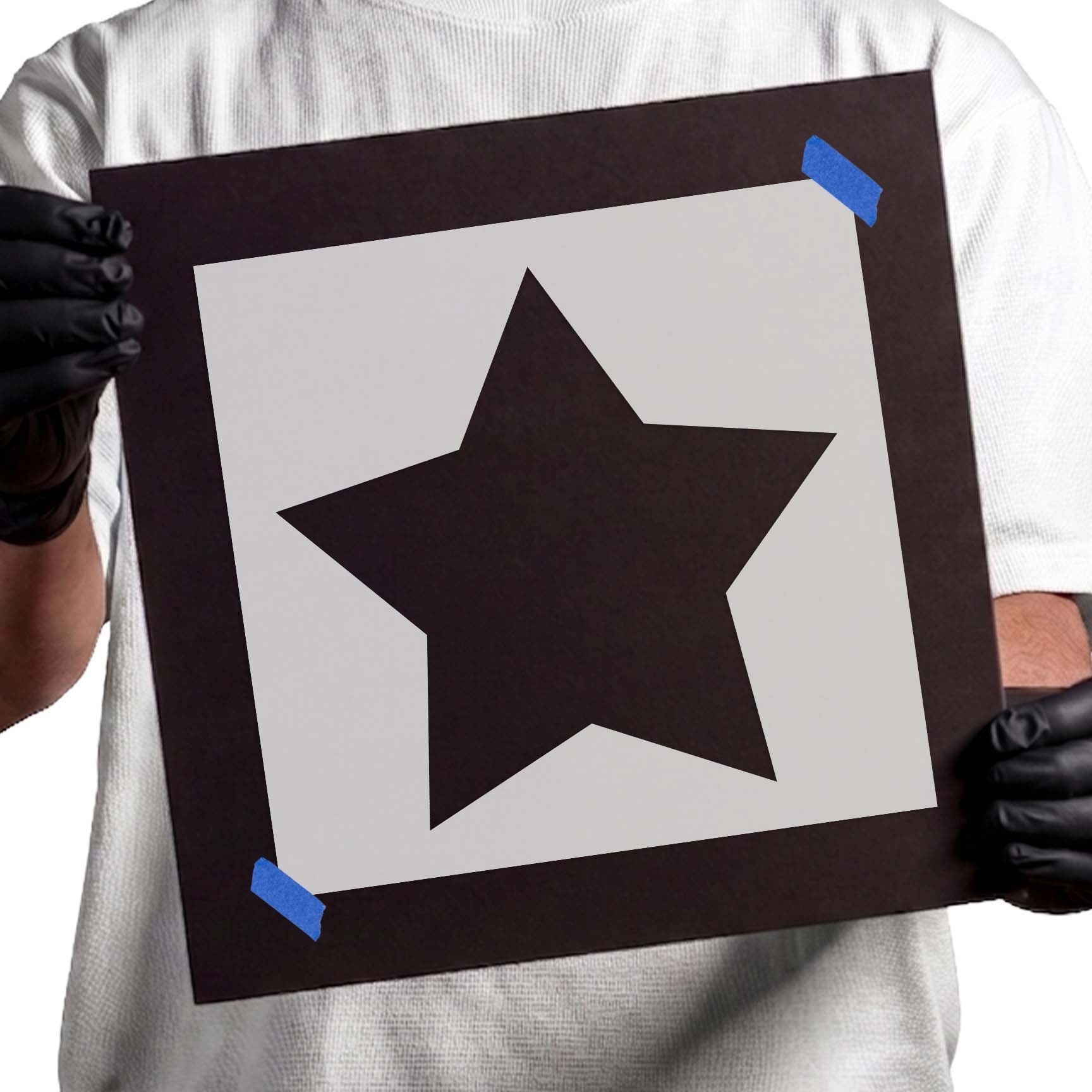 Person holding Classic Five-Point Star Stencil taped to black cardboard
