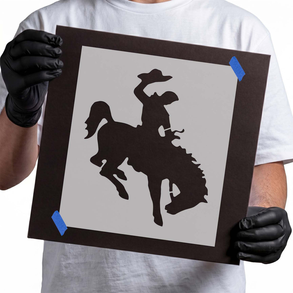 Cowboy stencil riding a bucking bronco with hat raised overhead