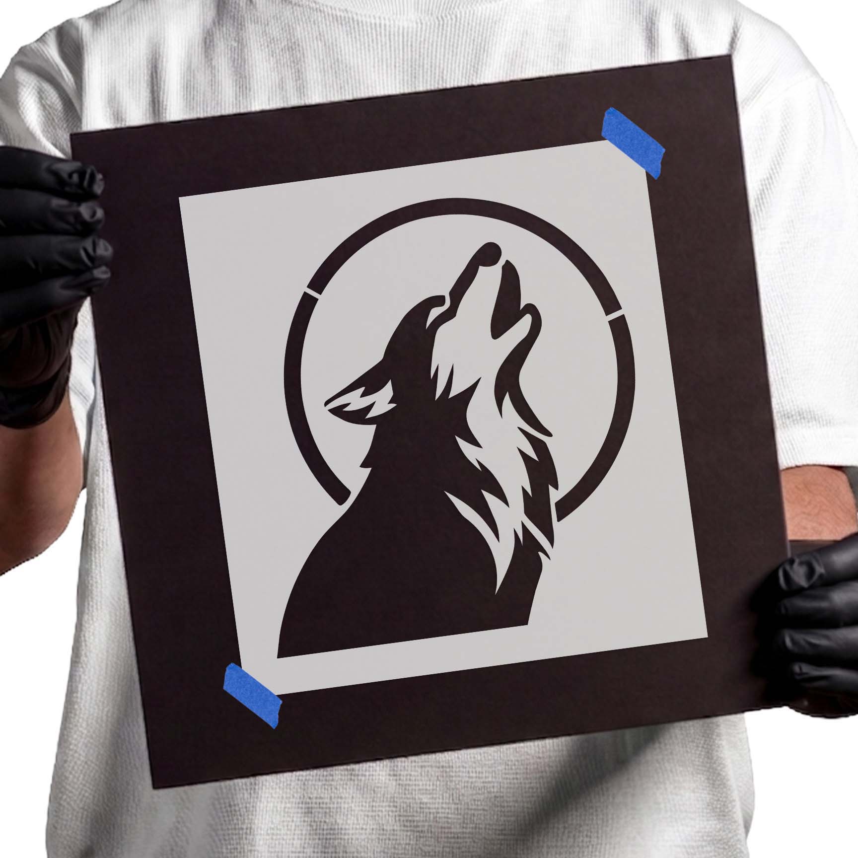 Person holding Dog Howling at Moon stencil taped to black cardboard