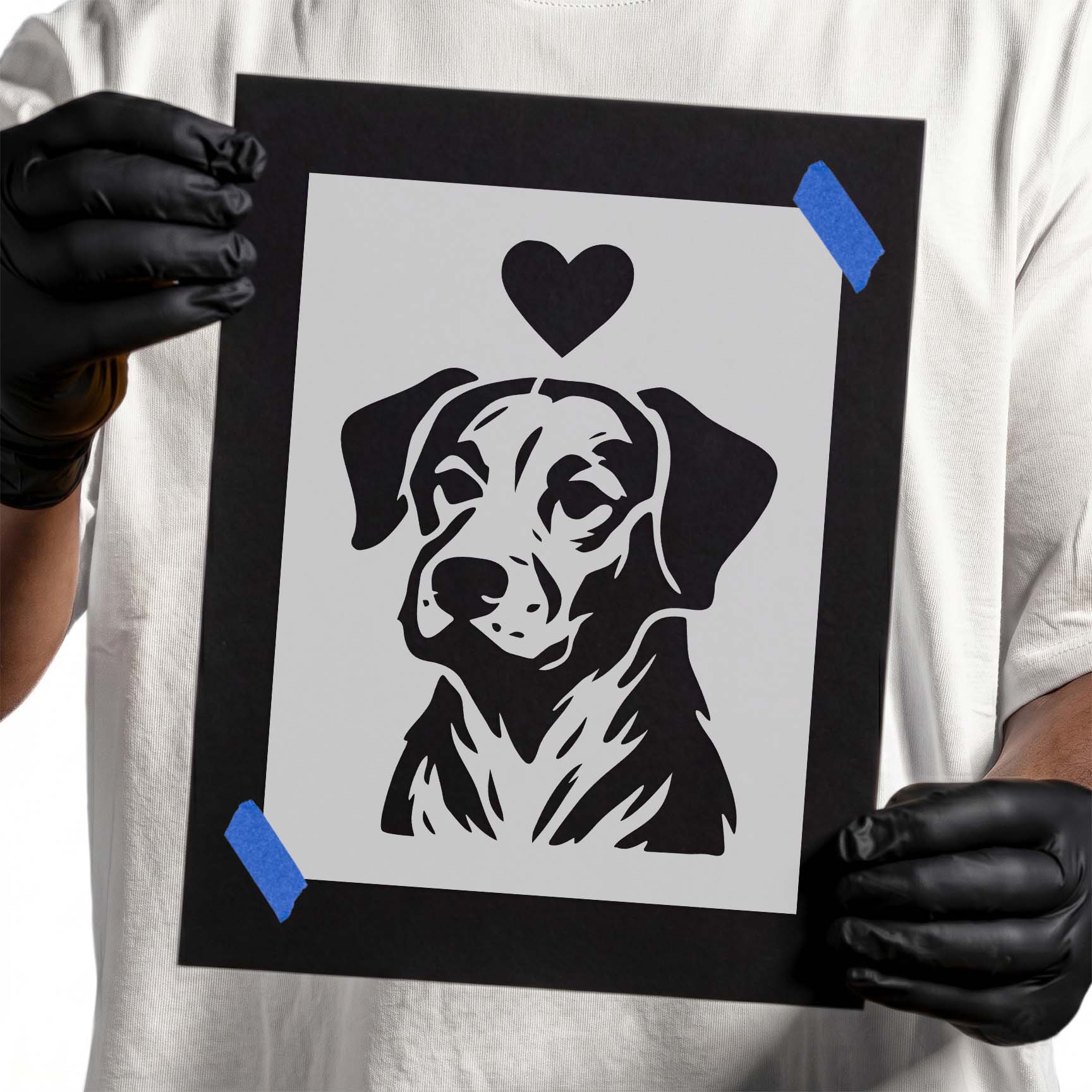 Person holding Dog Portrait with Heart stencil taped to black cardboard