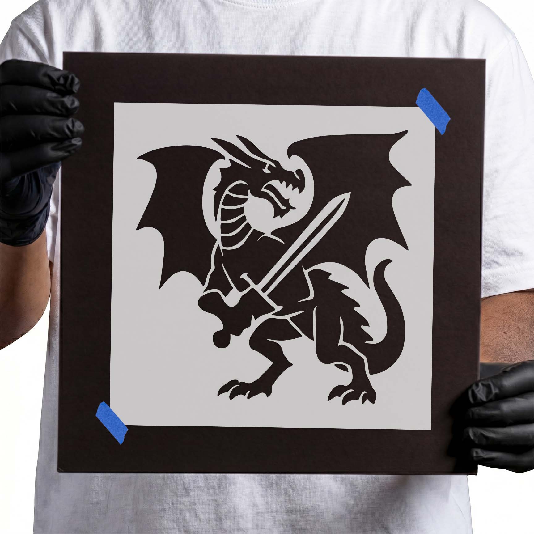 Person holding Dragon Knight Stencil taped to cardboard