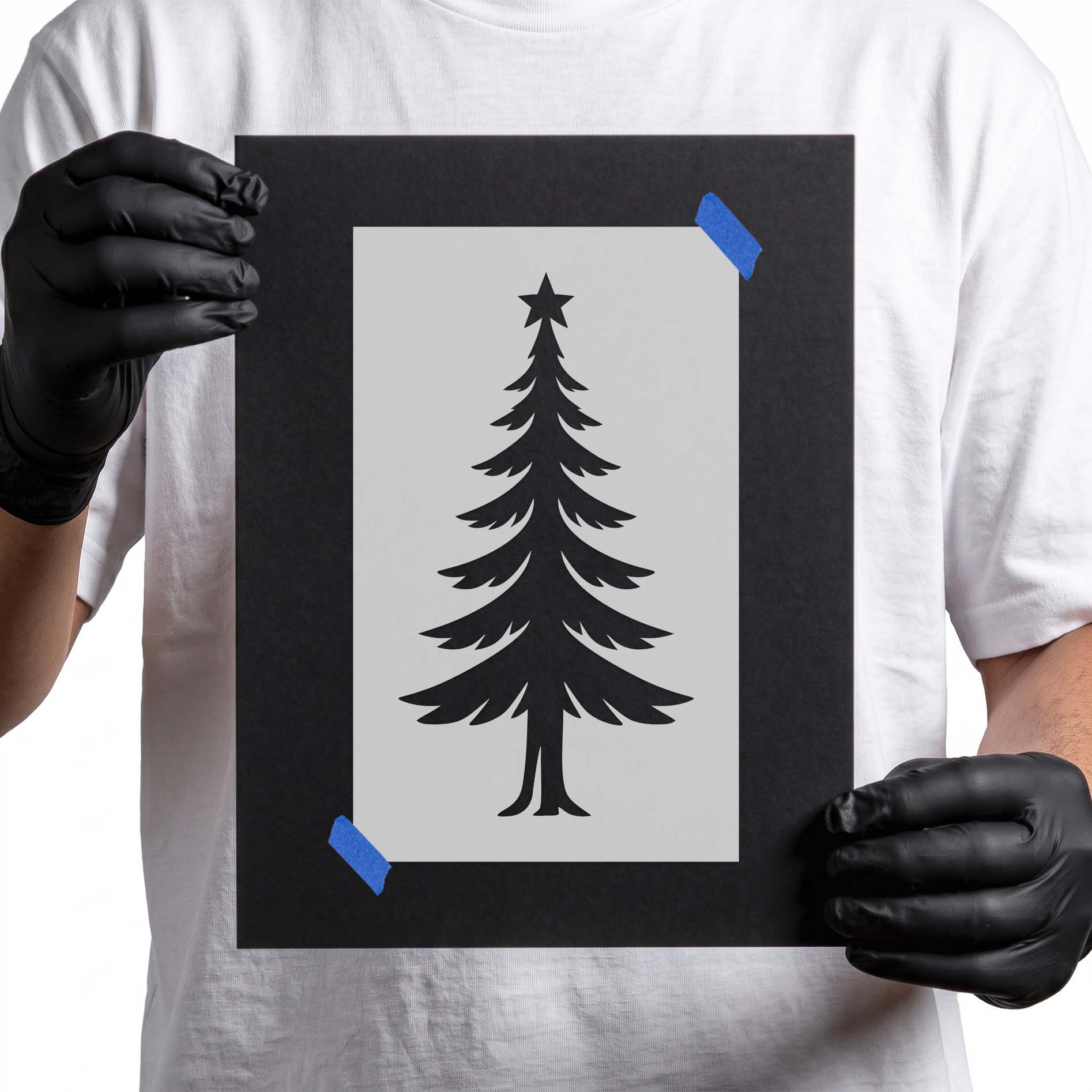 Person holding Elegant Slim Christmas Tree Stencil taepd to cardboard