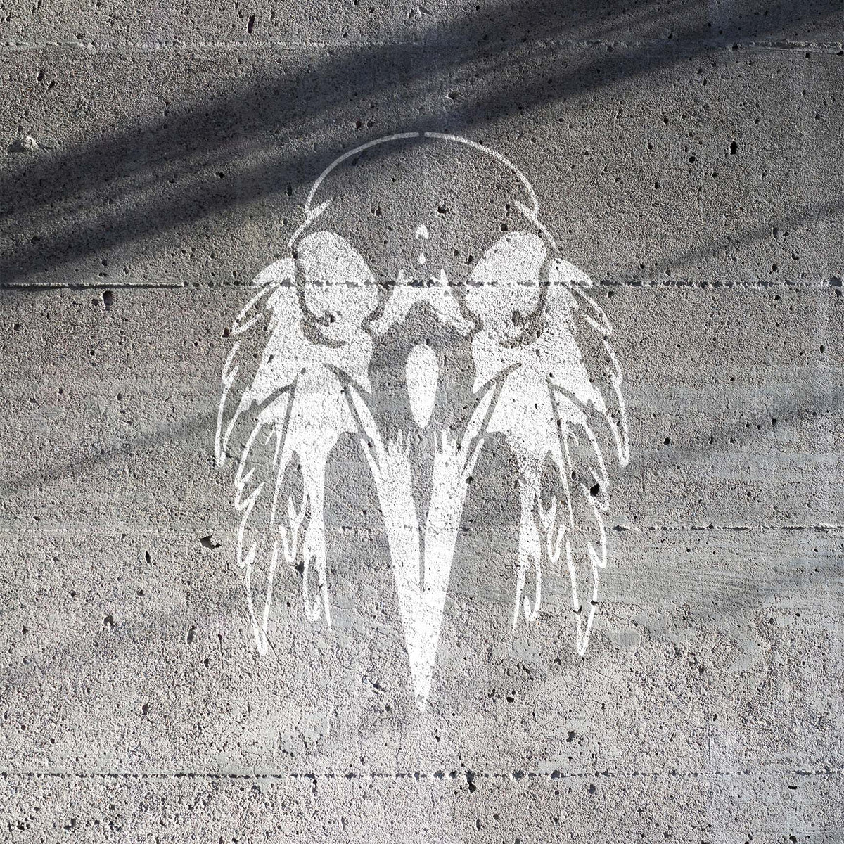 Ghostly white details reveal the Feathered Raven Skull Stencil against rough concrete