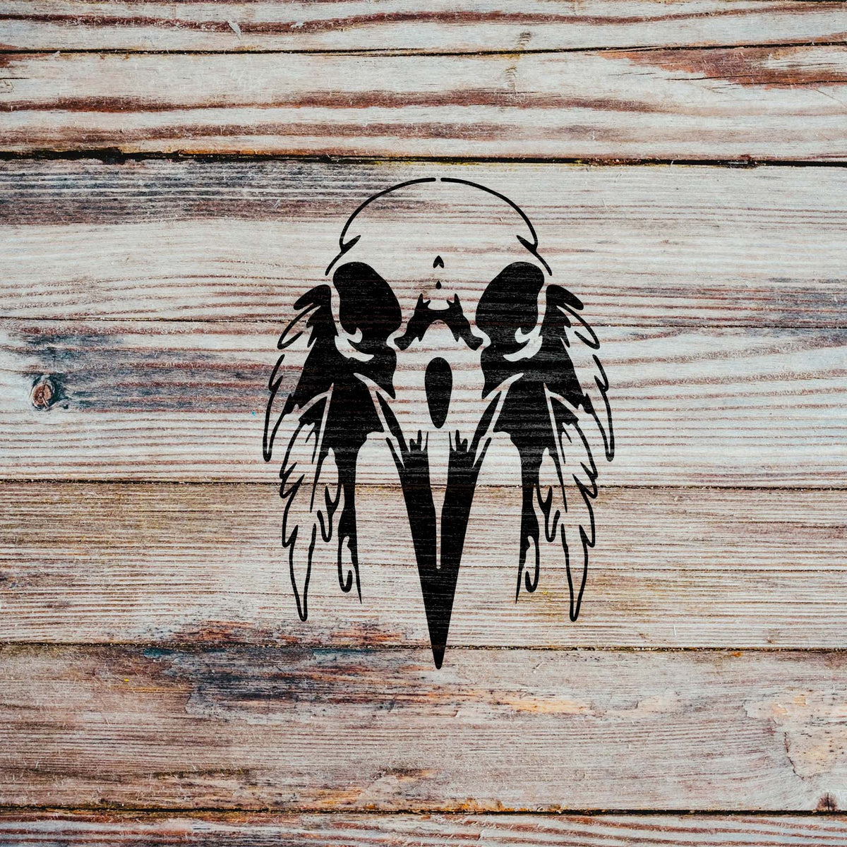 Rustic wood grain frames the bold beak and feathers of the Feathered Raven Skull Stencil