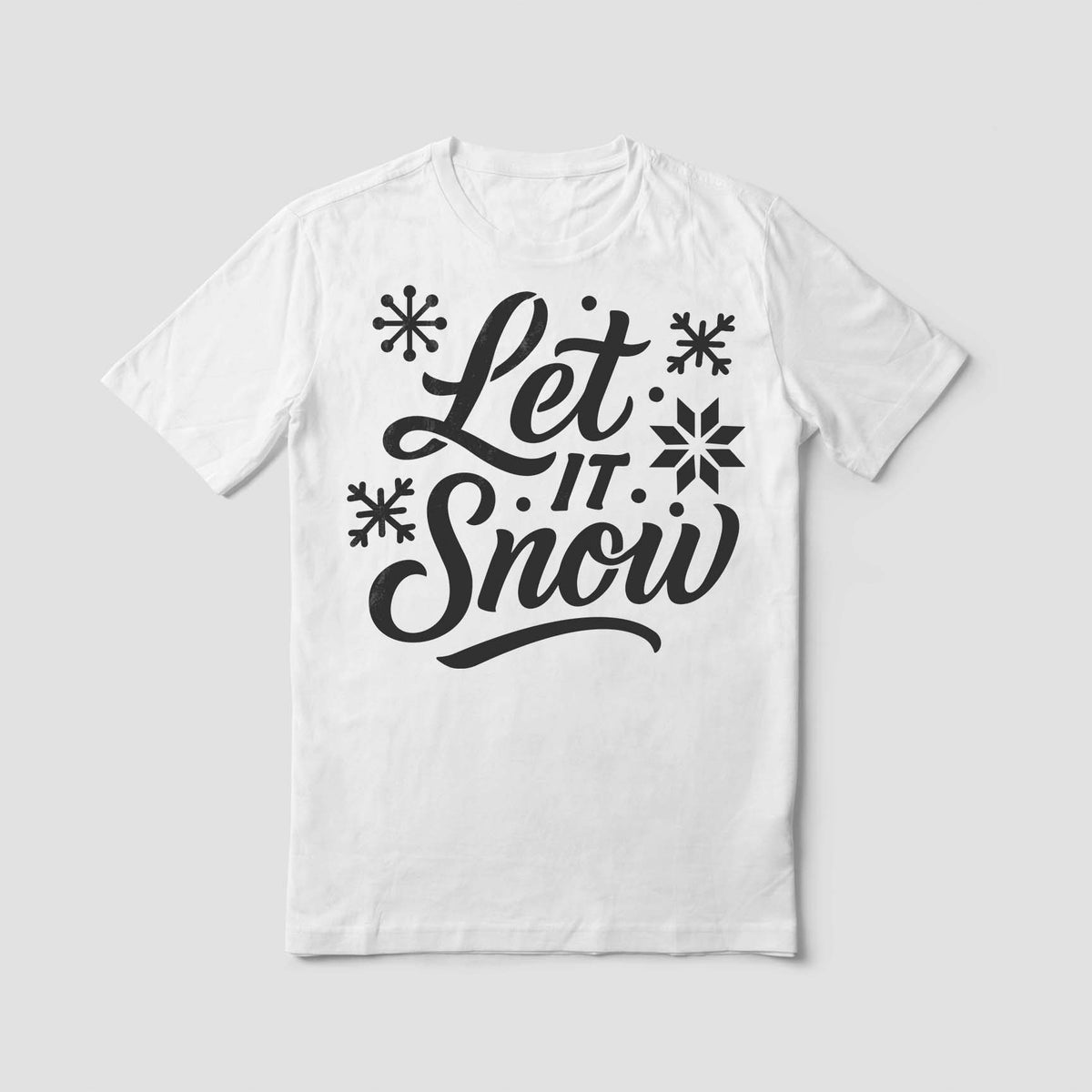 A white shirt features the Festive Let It Snow Text Stencil with bold script and scattered snowflakes.