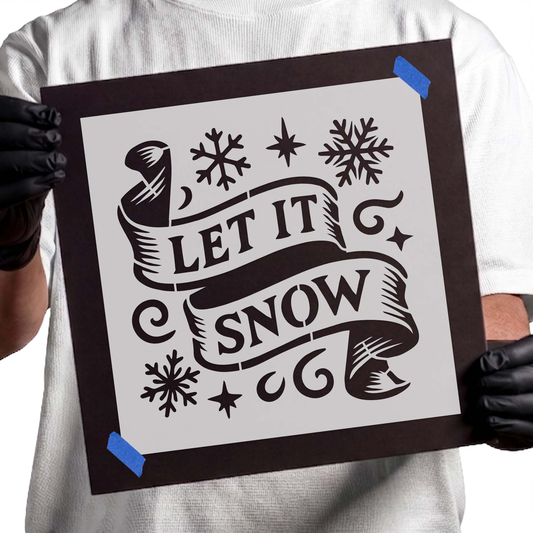 Decorative Let It Snow banner stencil featuring an elegant ribbon scroll with festive snowflakes, stars, and winter holiday accents