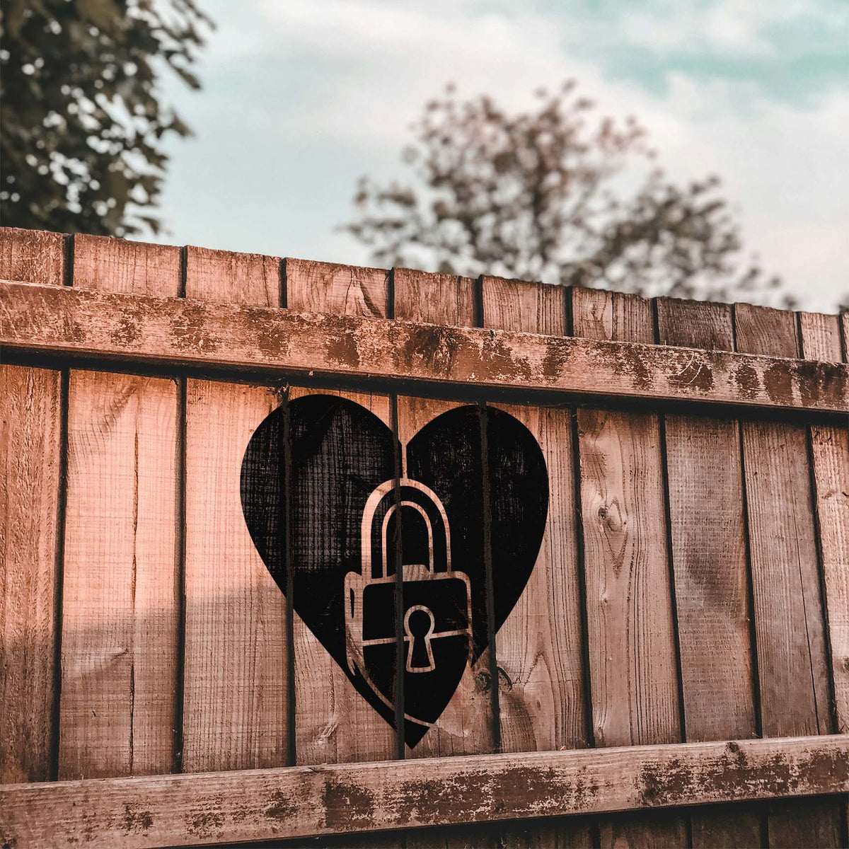 Rustic wood fence displays the Love Lock Heart Stencil with a striking black padlock design
