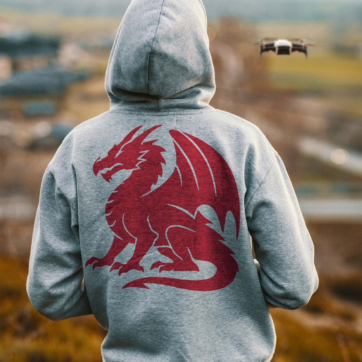 A fierce red Majestic Sitting Dragon Silhouette Stencil adorns a gray hoodie's back with wings and a curled tail.