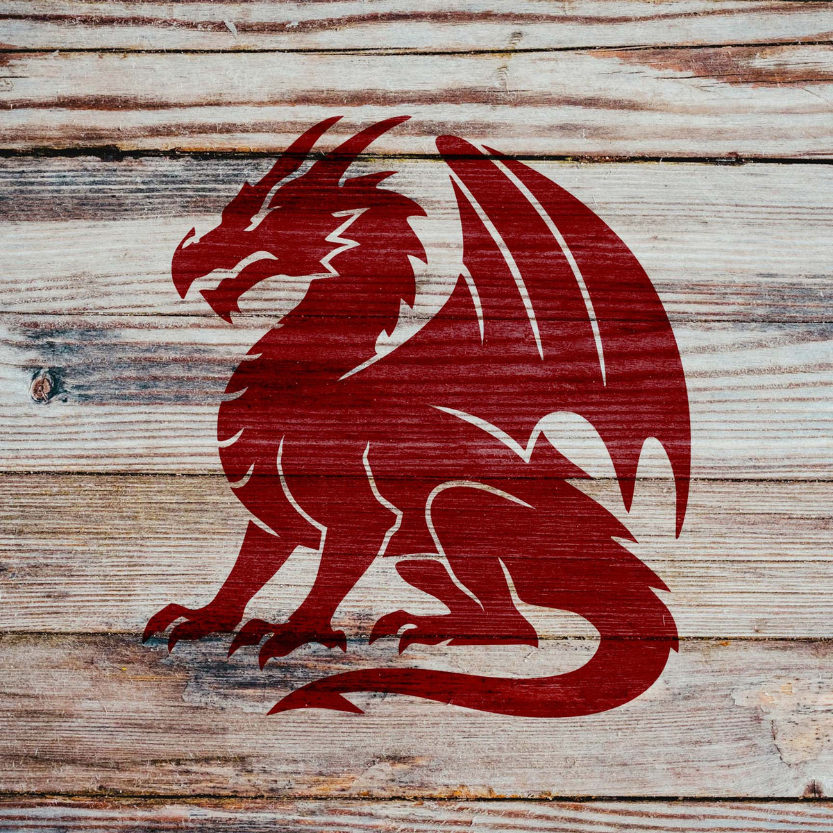 Sweeping wings and sharp claws define the Majestic Sitting Dragon Silhouette Stencil on rustic wooden planks.