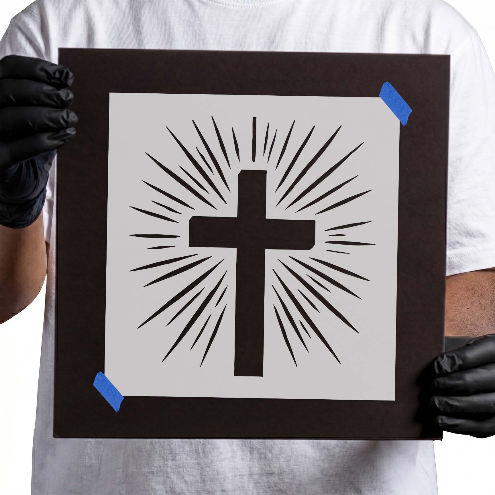 Person holding Radiant Cross stencil taped to black cardboard