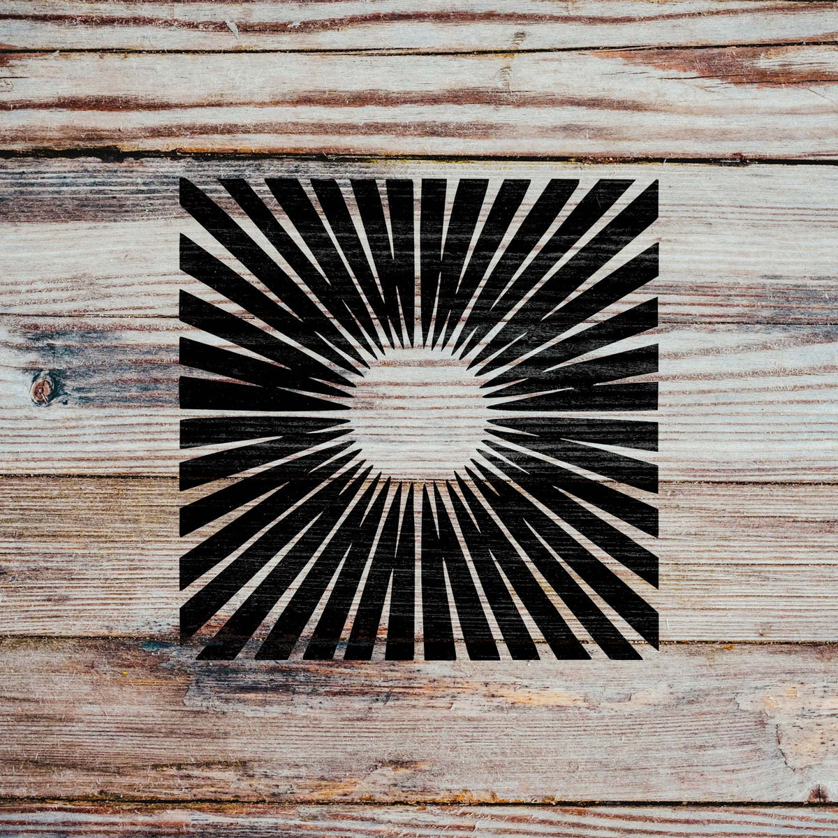 Radiant Sunburst Stencil displays crisp black rays across wooden planks