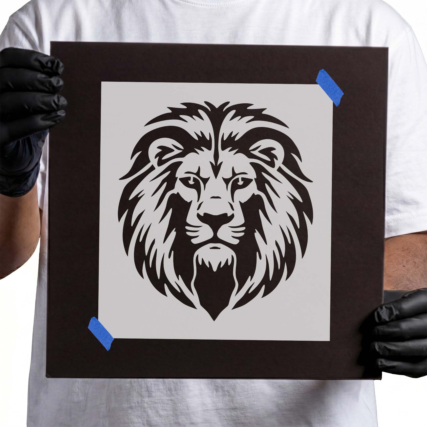 Person holding Regal Lion Head Stencil taped to cardboard