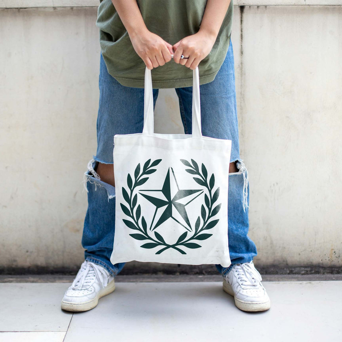 A white tote bag features the Rustic Star Laurel Wreath Stencil framed by graceful leafy branches