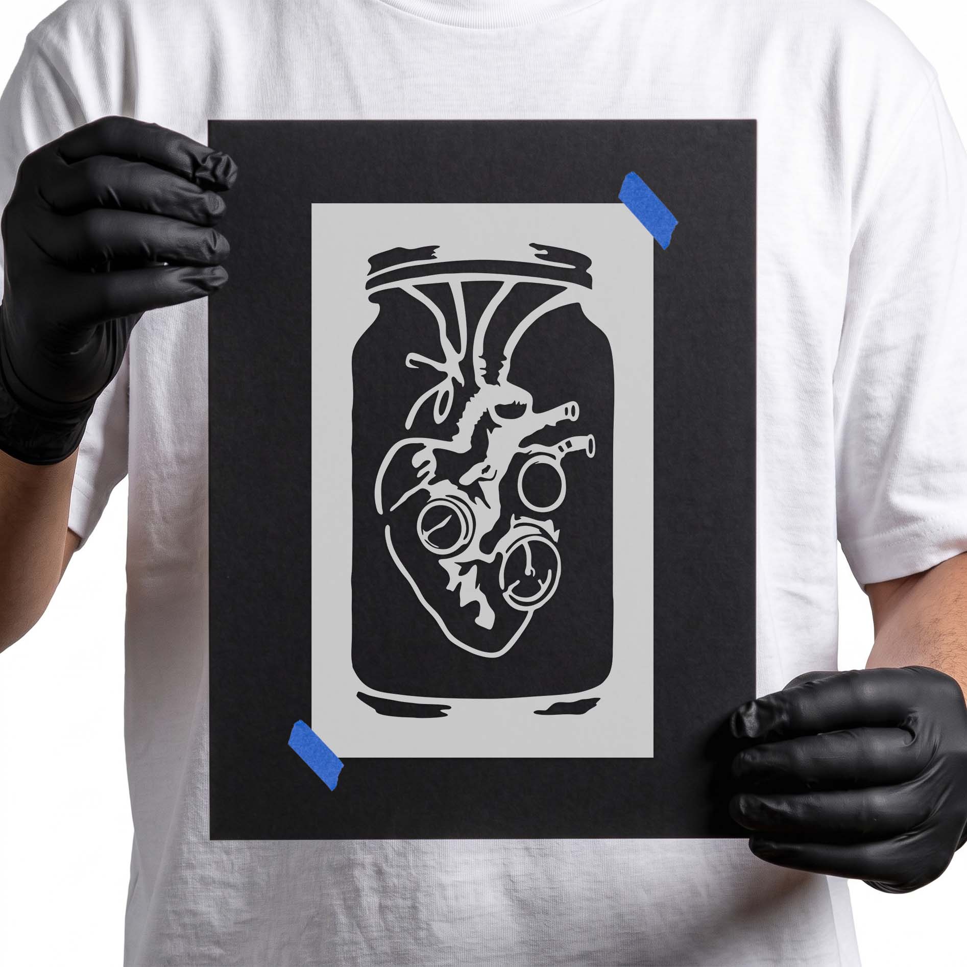 Person holding Steampunk Anatomical Heart Jar Stencil taped to cardboard