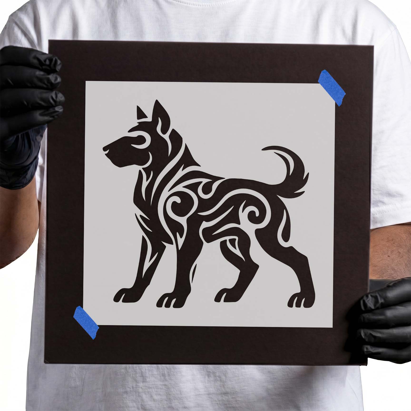 Person holding Tribal Dog Silhouette Stencil taped to cardboard