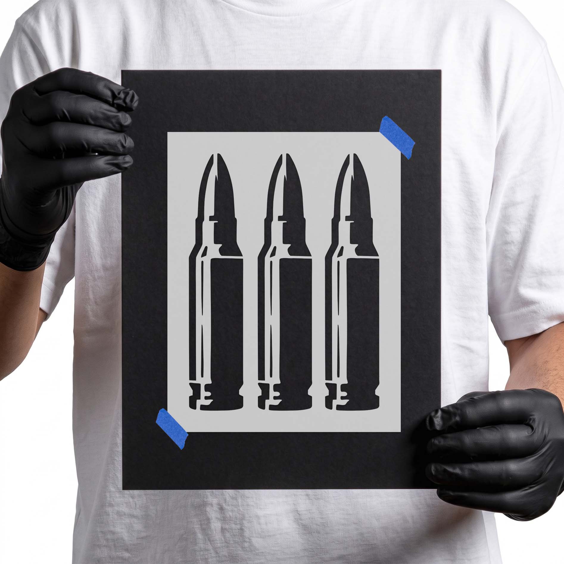 Gloved hands holding Triple Rifle Cartridge Stencil taped to black cardboard