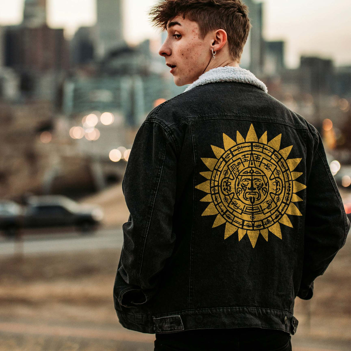 Golden Aztec Sun Calendar Stencil stands out across the back of a black denim jacket