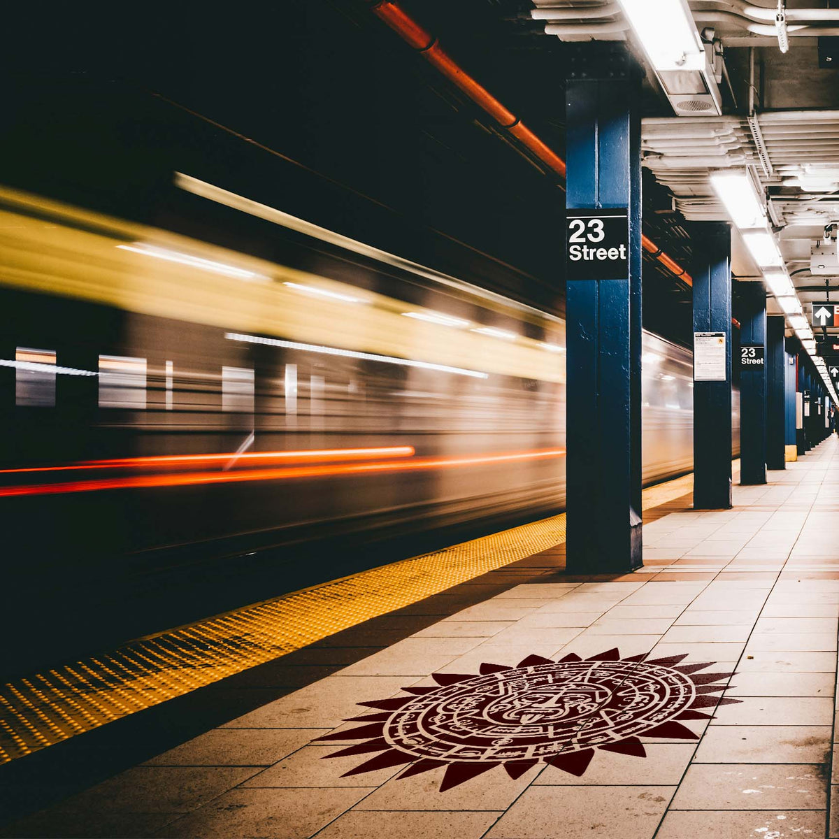 A burgundy Aztec Sun Calendar Stencil decorates the tiled floor beside a passing subway train