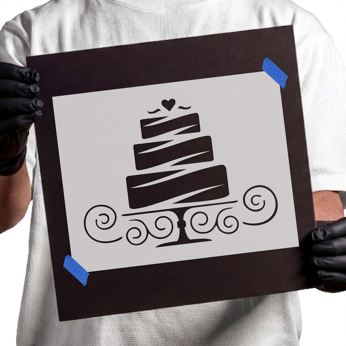 Three tiered cake stencil with heart topper, diagonal icing details, pedestal stand, and swirling flourishes