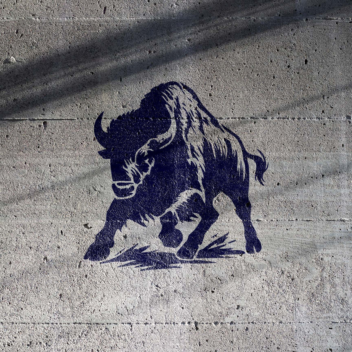 Stampeding Bison Stencil painted navy on a textured concrete wall with dynamic charging pose.