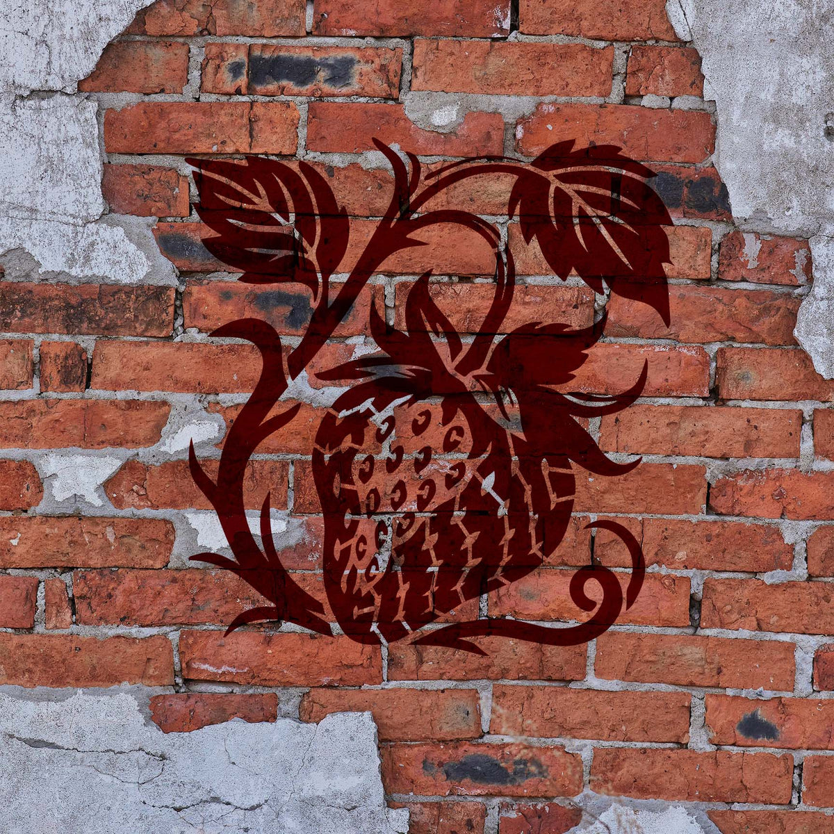 Rich burgundy Botanical Strawberry Vine Stencil decorates a weathered red brick wall.
