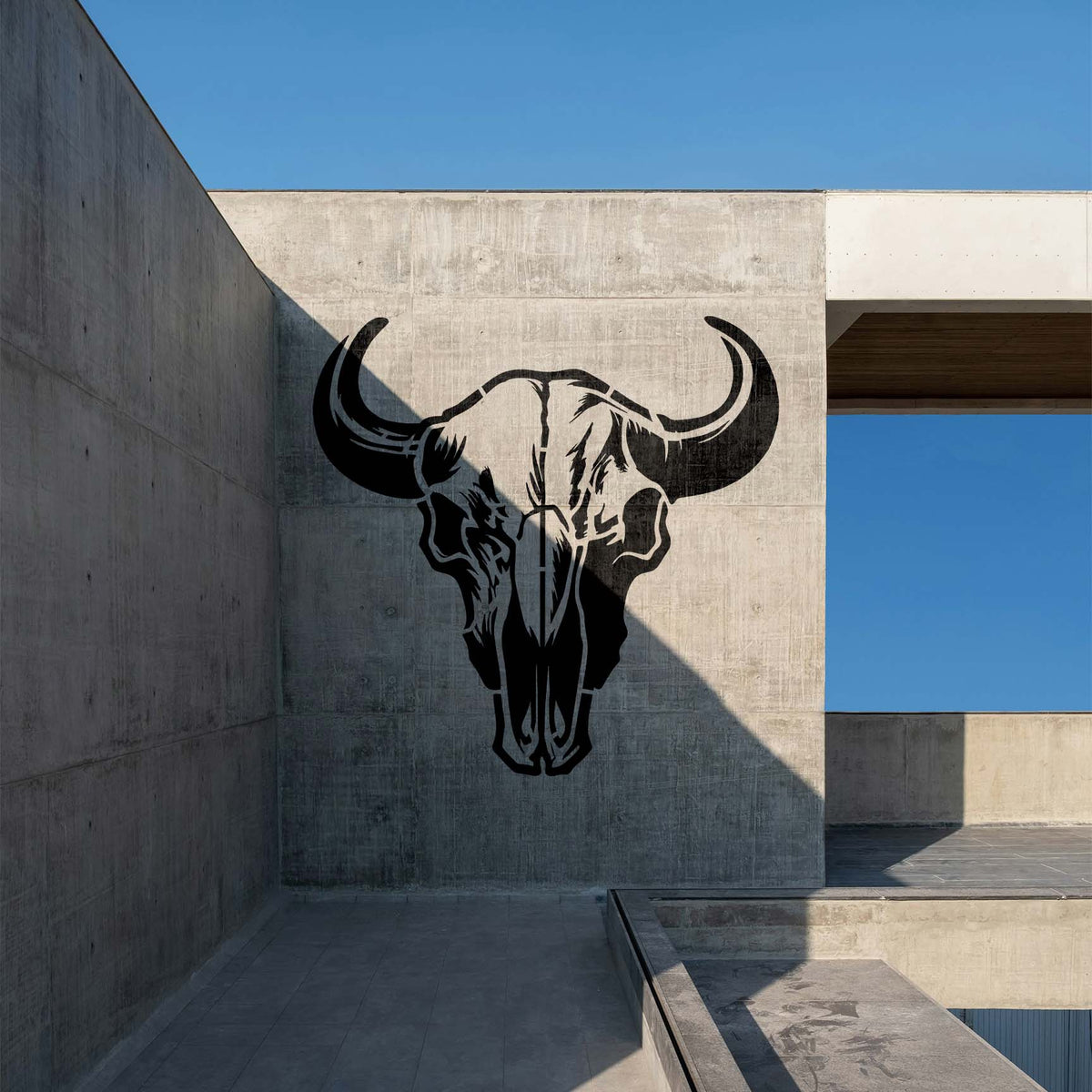 Across a modern concrete wall, the Buffalo Skull Stencil reveals striking black horns and skull details.