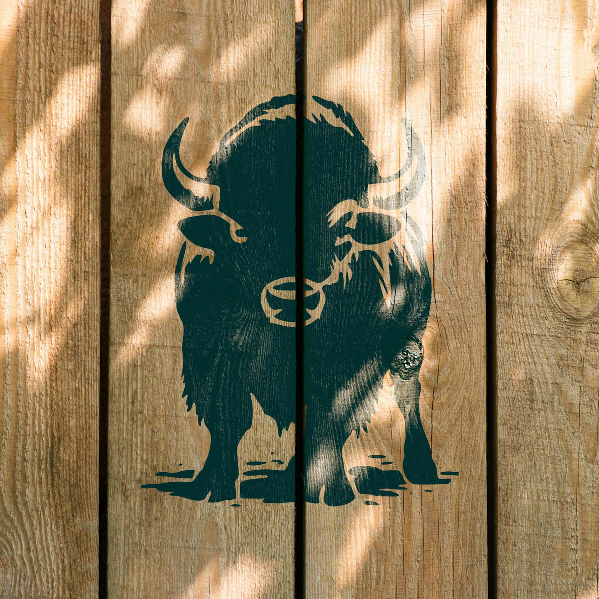 Front Facing Bison Stencil painted dark green across rustic wooden fence boards with bold horns.