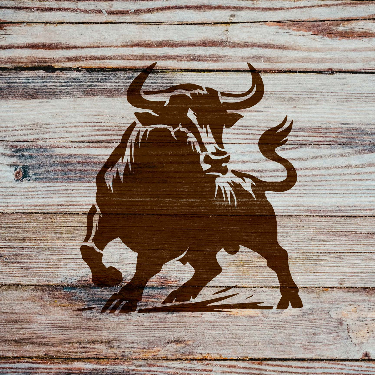 Charging Bull Stencil painted on rustic wood with a charging horned bull design.
