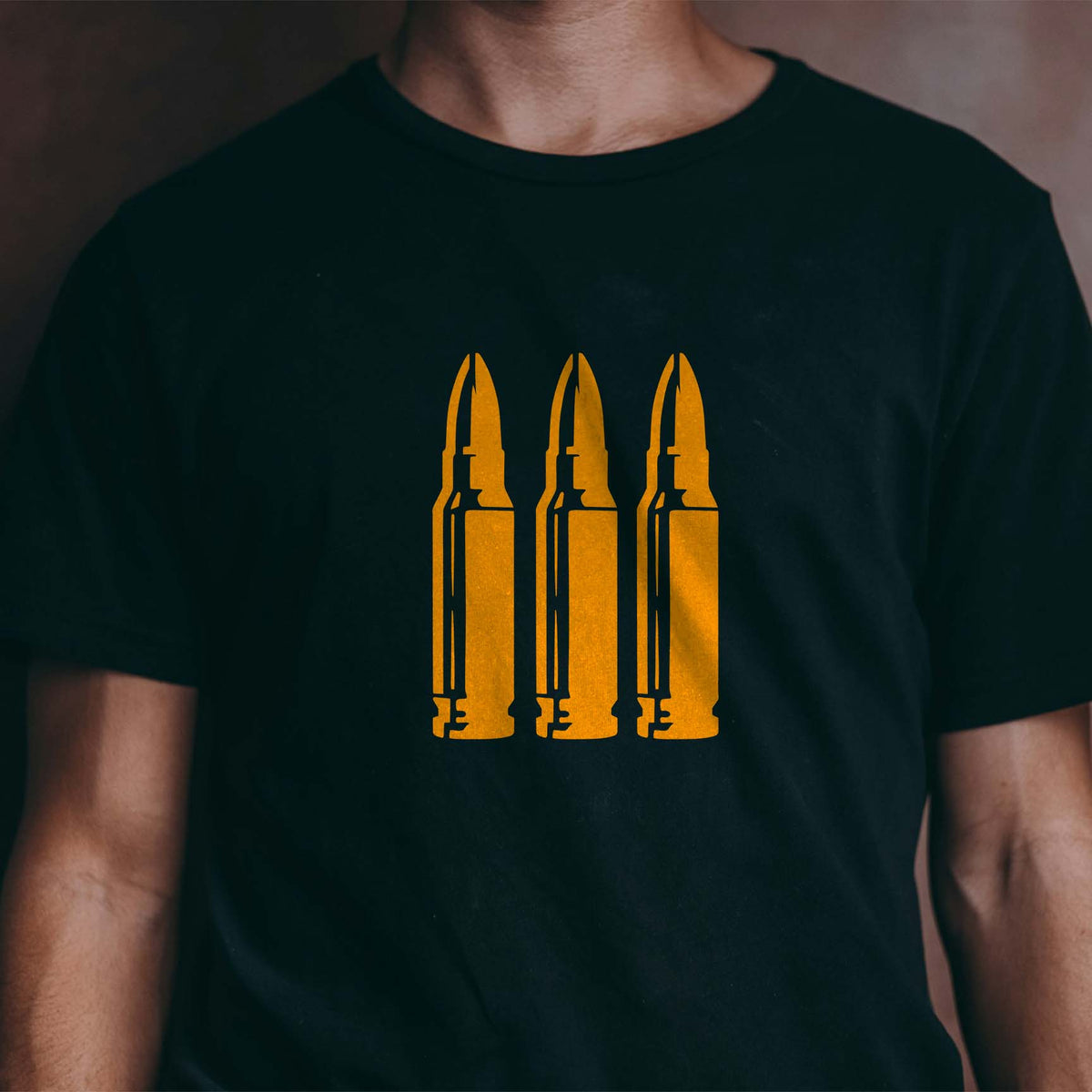 Triple Rifle Cartridge stencil stands out in gold across a black shirt