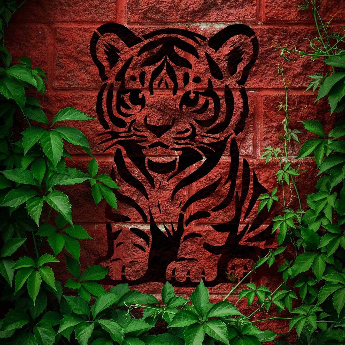 Cartoon Tiger Cub Stencil depicts a seated baby tiger in black on a red brick wall surrounded by ivy.