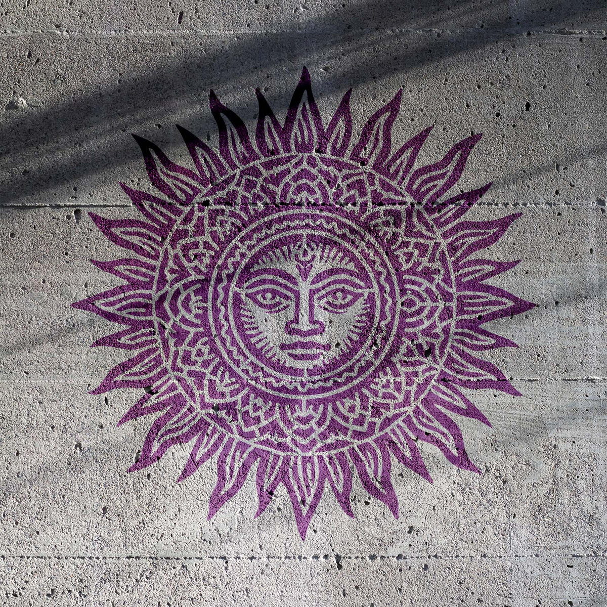 Purple Celestial Mandala Sun Stencil reveals an intricate sun face on textured gray concrete.
