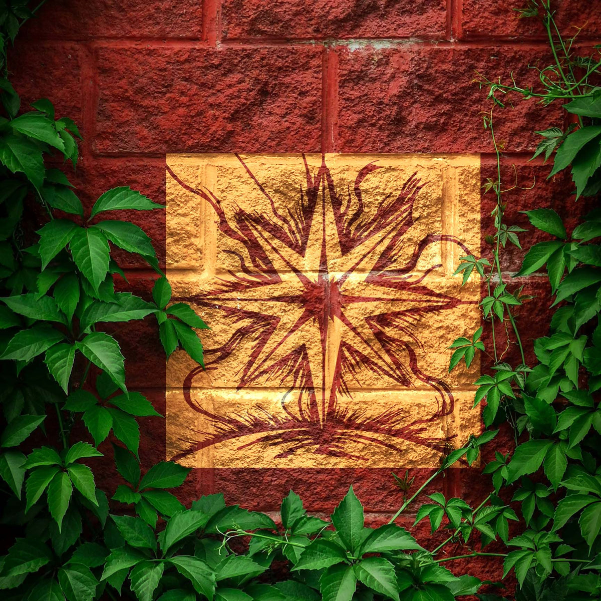 Celestial Starburst Stencil glows in gold and red across a leafy brick wall
