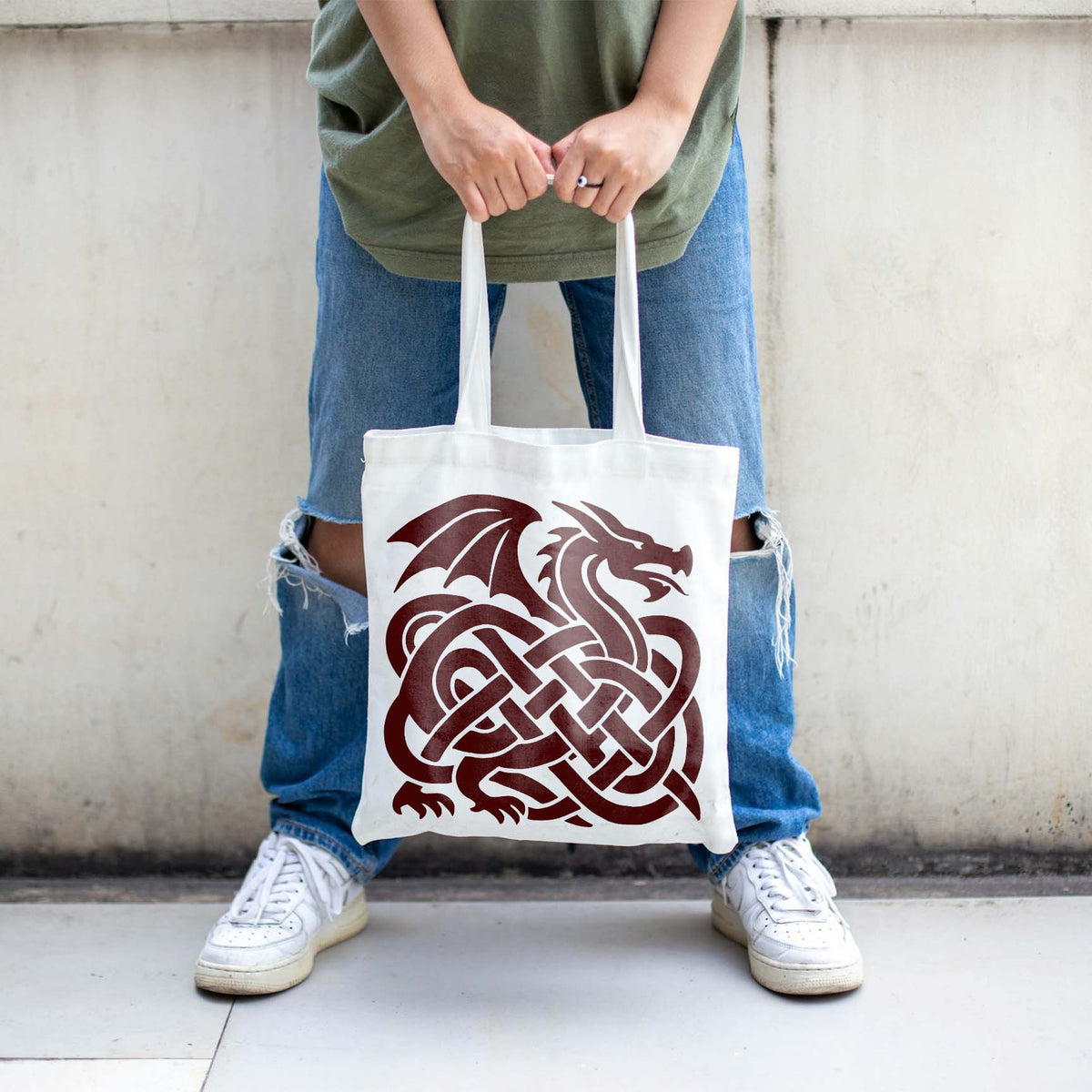 Intricate Celtic loops form a bold dragon in the Celtic Dragon Knot Stencil featured on a white tote bag.