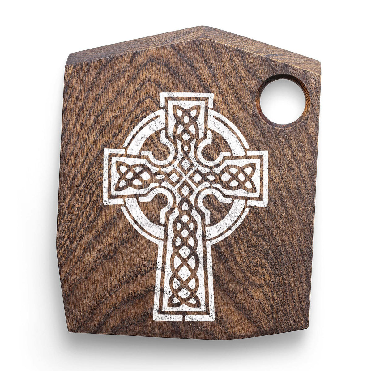 Celtic Knot Cross Stencil engraved in white on a dark wooden cutting board.