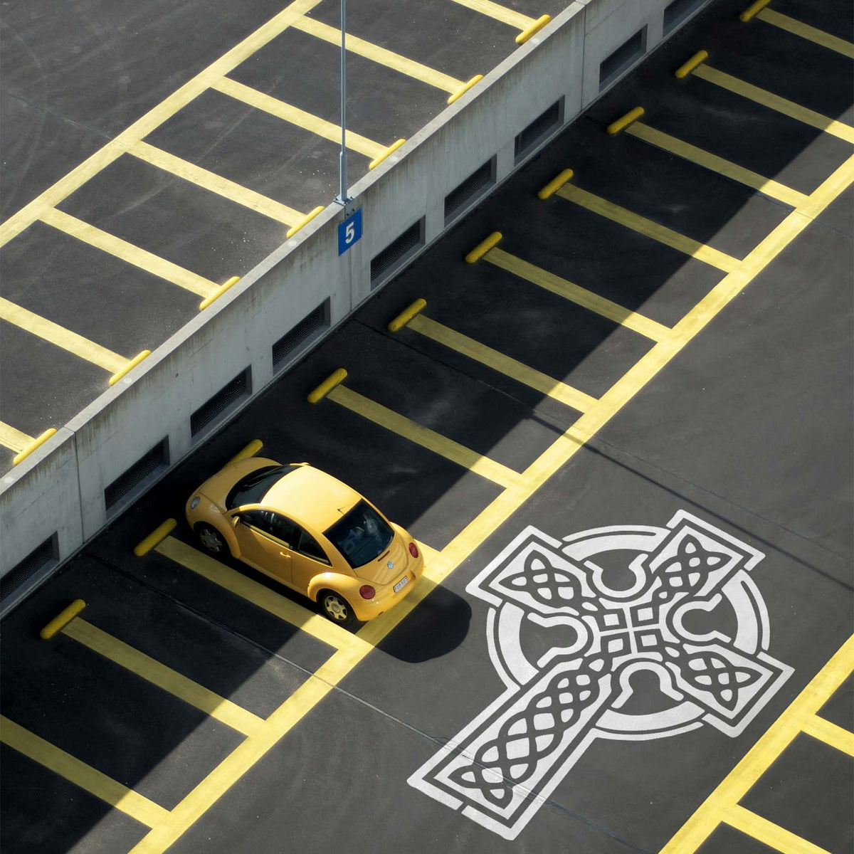 Celtic Knot Cross Stencil painted in white across a rooftop parking lot.