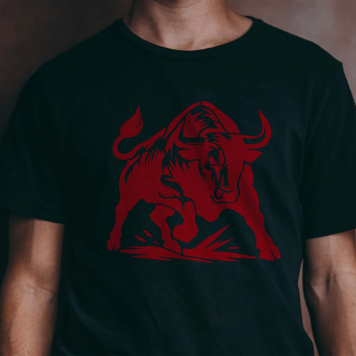 A fierce red Charging Bull Silhouette Stencil with curved horns and raised hooves stands out on a black T-shirt.