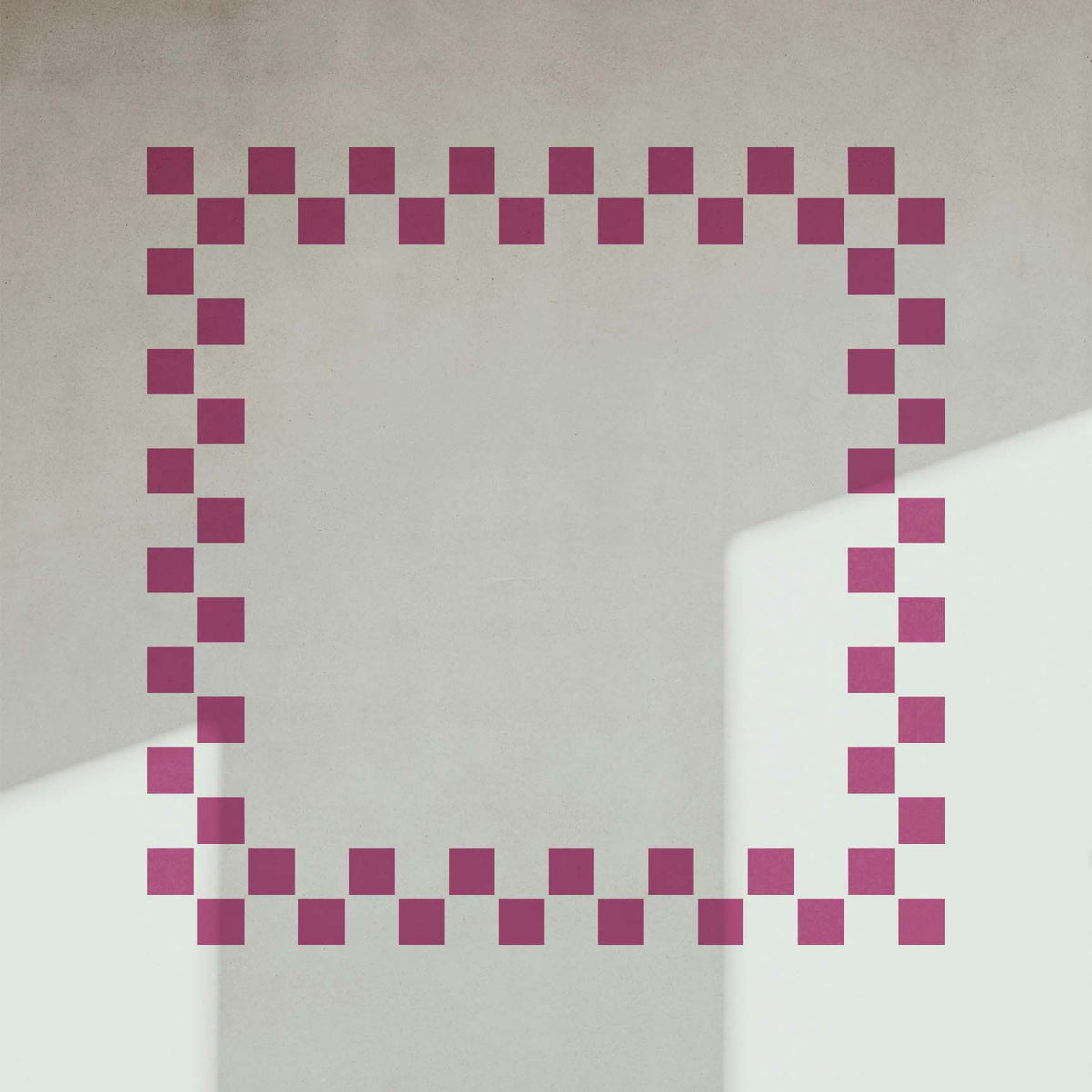 Checkerboard Border Frame Stencil creates a charming pink geometric border on a sunlit white wall.