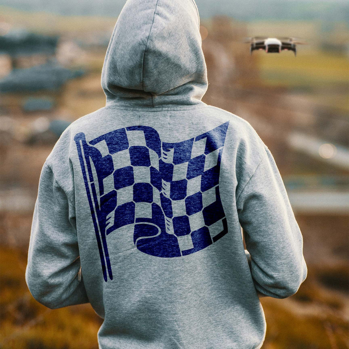 Checkered Racing Flag Stencil appears in blue on a gray hoodie worn outdoors.