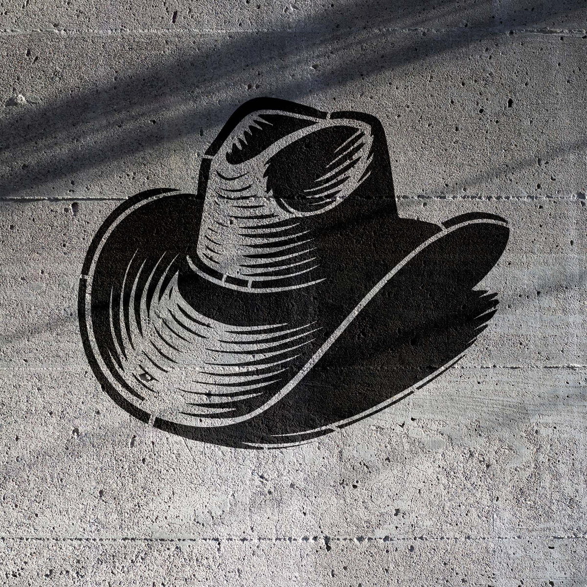 A black Classic Cowboy Hat Stencil shows a wide curved brim and detailed crown on a gray concrete wall.