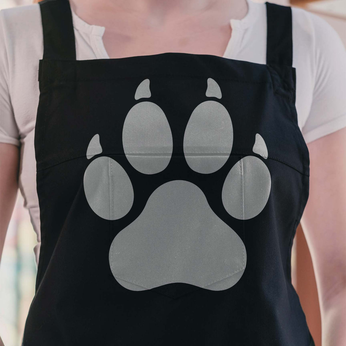 Clawed Paw Print Stencil stands out in silver across a black apron with four pointed claws
