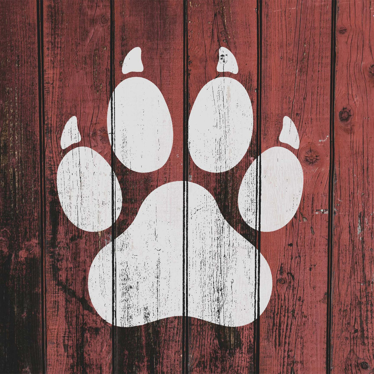 Weathered red wood displays the Clawed Paw Print Stencil as a large distressed white paw mark