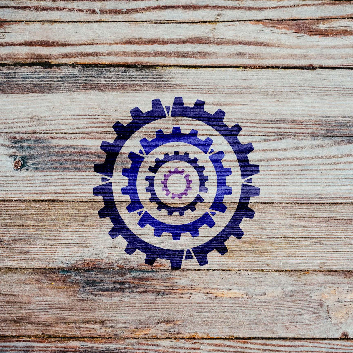 Concentric Cogs stencil with nested blue and purple gear design on rustic wood surface