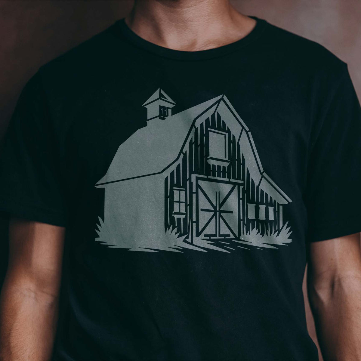 A Countryside Barn Facade Stencil brings rustic farmhouse charm to a black T-shirt.