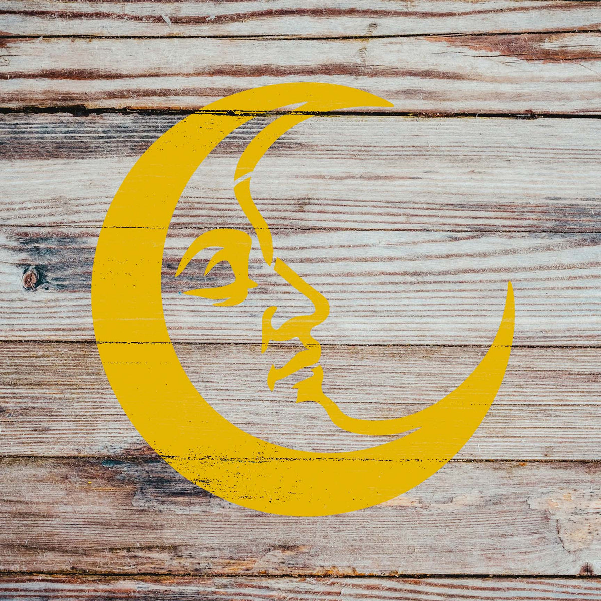 Weathered wooden planks showcase the Crescent Moon Face Stencil in sunny yellow with a serene expression.