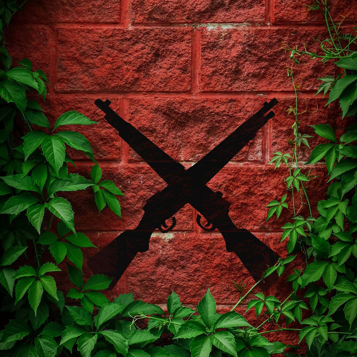 Crossed Rifles Silhouette stencil displayed on red brick wall with greenery