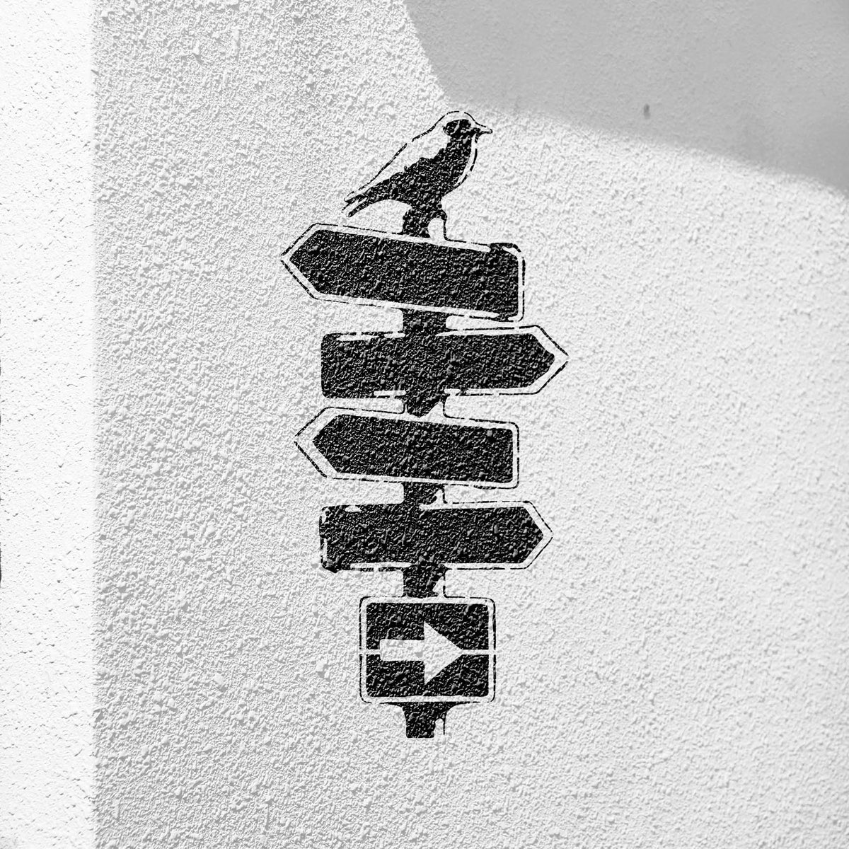 Crow on Rustic Signpost Stencil painted on a textured white wall with angled sunlight.