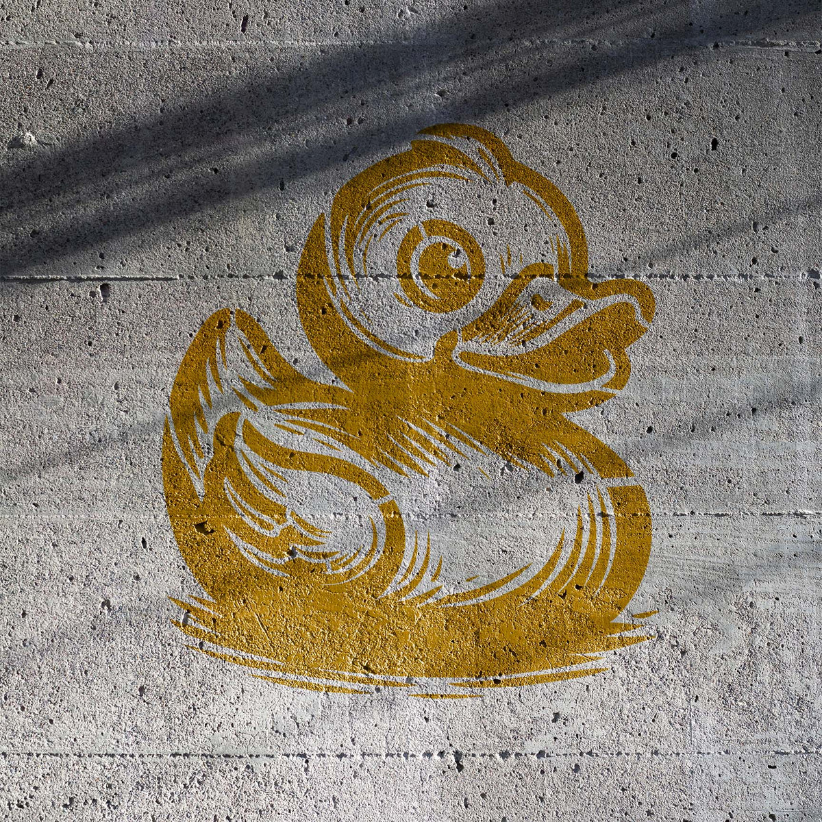 Sprayed on concrete, the Cute Rubber Duck Stencil shows a yellow duck with a cheerful expression.